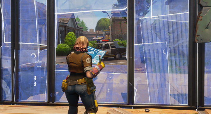Ein weiblicher Charakter editiert im Fortnite Kreativmodus ein Fenster in eine Metallwand und hat den Bauplan in der Hand