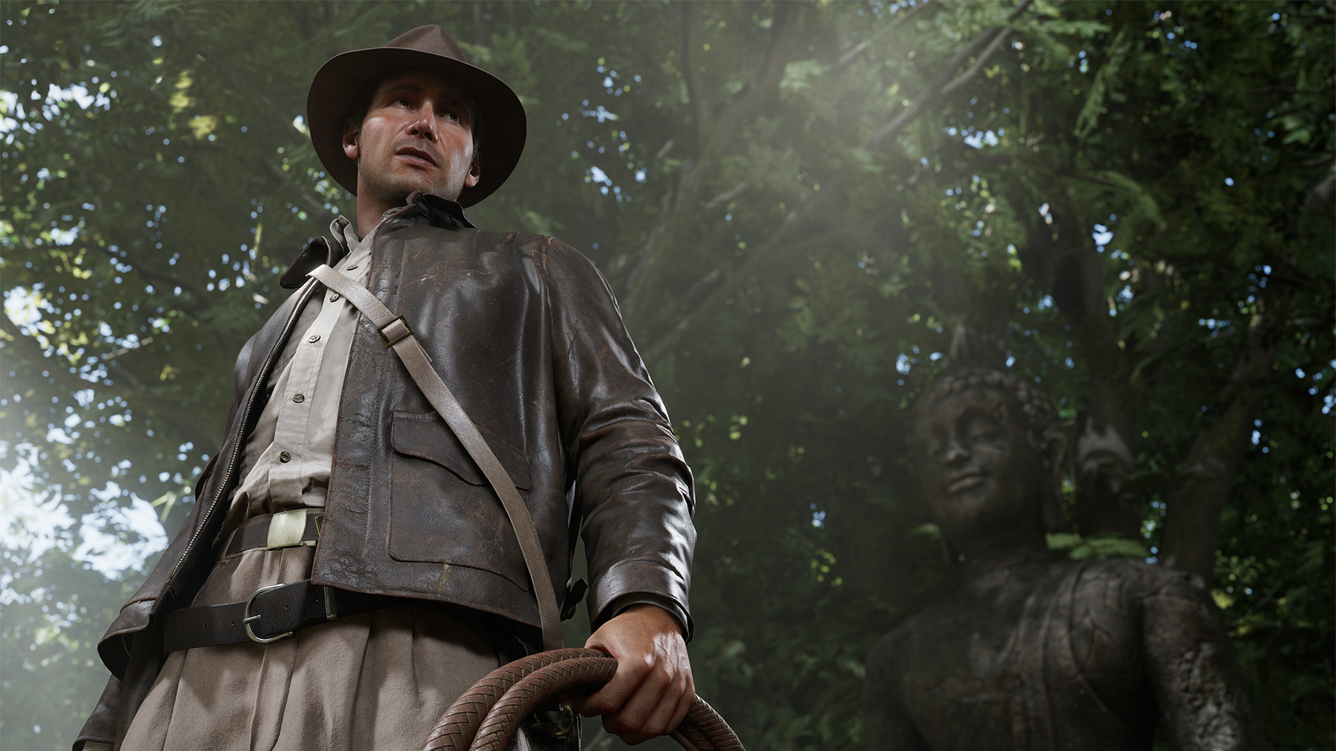 Indiana Jones steht mit Lederjacke und Hut im Wald und hält seine Peitsche